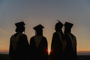 four TAP students wearing graduation robes